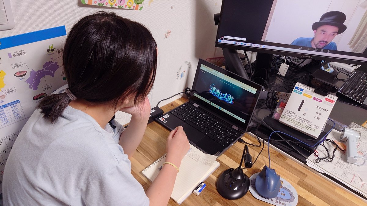 パソコンと大きな画面を使って自宅で受講する後ろ姿